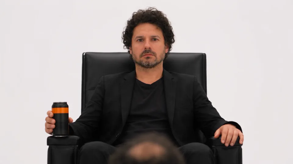 Una figura de traje con una lata en la mano, frente a José Luis, sobre un fondo blanco